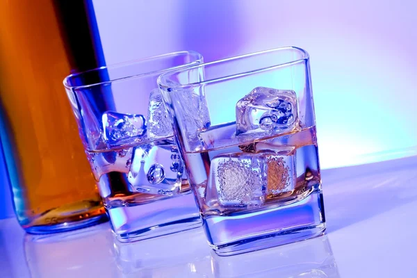 Um par de copos de bebida alcoólica com gelo na luz azul disco — Fotografia de Stock