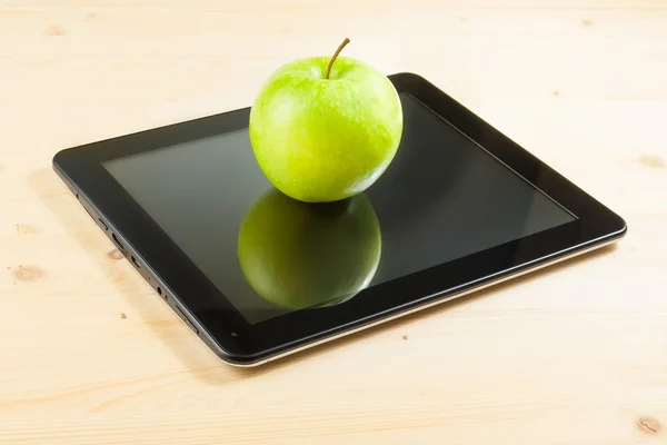 Zelené jablko na digitální počítače tablet pc na dřevěný stůl — Stock fotografie