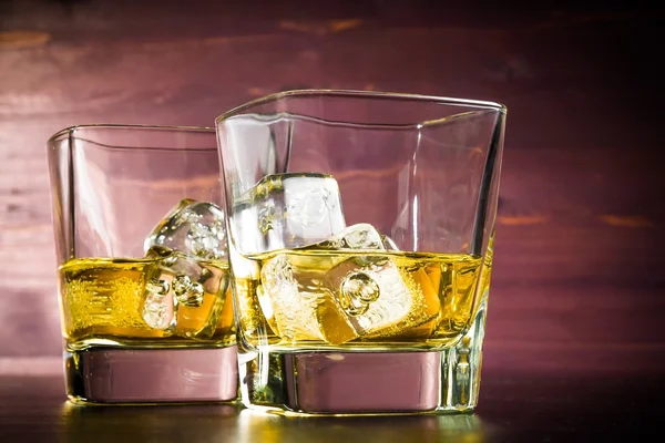 Dvě sklenice whisky s ledem na starý dřevěný stůl — Stock fotografie