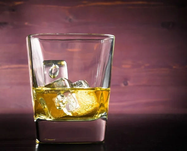 Serie de bebidas, un vaso de whisky con hielo en la vieja mesa de madera — Foto de Stock
