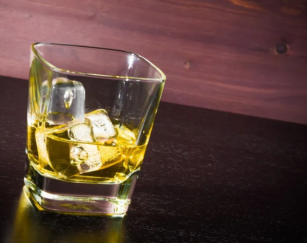 Nápoj série, jednu sklenici whisky s ledem na starý dřevěný stůl — Stock fotografie