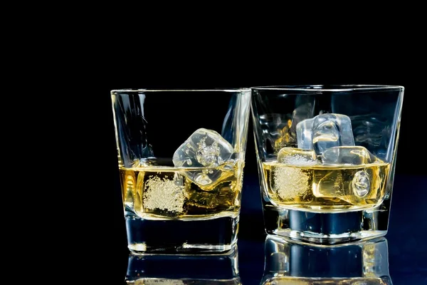 Dvě sklenice alkoholického nápoje s ledem na disco modré světlo — Stock fotografie
