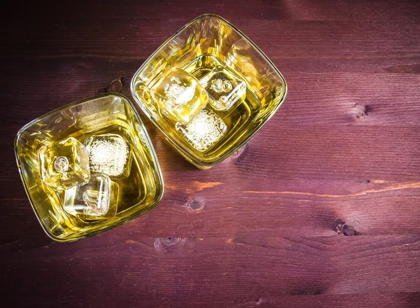 Top of view of two glasses of whiskey with ice on old wood table background — Stock Photo, Image