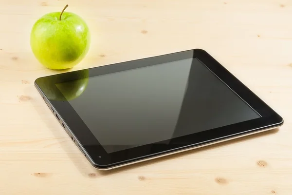 Digital tablet pc near green apple on wood table — Stock Photo, Image