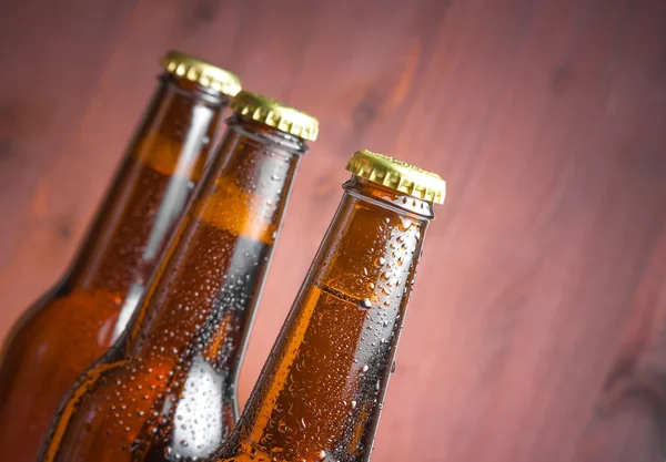 Three tilted bottles of fresh beer with drops and space for text — Stock Photo, Image