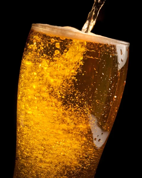 Detail of fresh beer pouring from bottle into glass — Stock Photo, Image