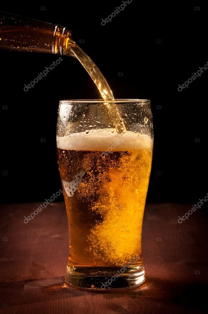 Fresh beer pouring from bottle into glass — Stock Photo © donfiore1 43777363