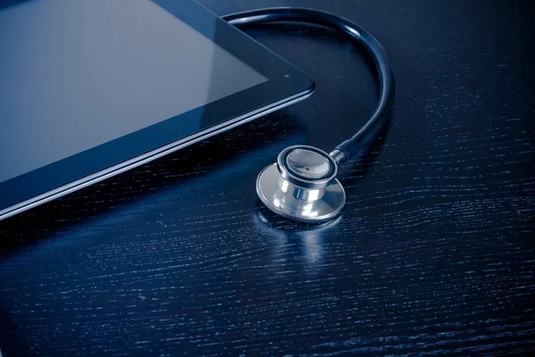 Estetoscópio médico no moderno tablet digital pc em laboratório na mesa de madeira — Fotografia de Stock