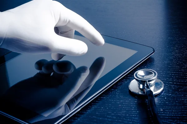 Mão na luva médica tocando moderno tablet digital pc perto do estetoscópio — Fotografia de Stock