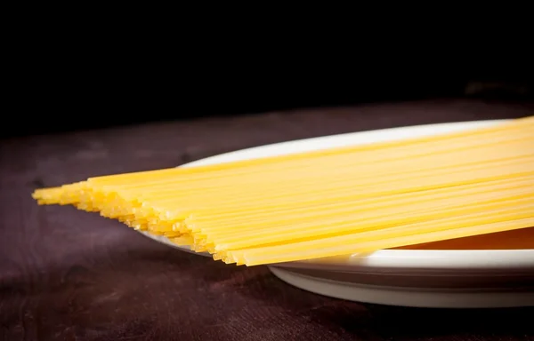 Ruwe pasta spaghetti op vlakke over houten tafel met ruimte voor tekst — Stockfoto