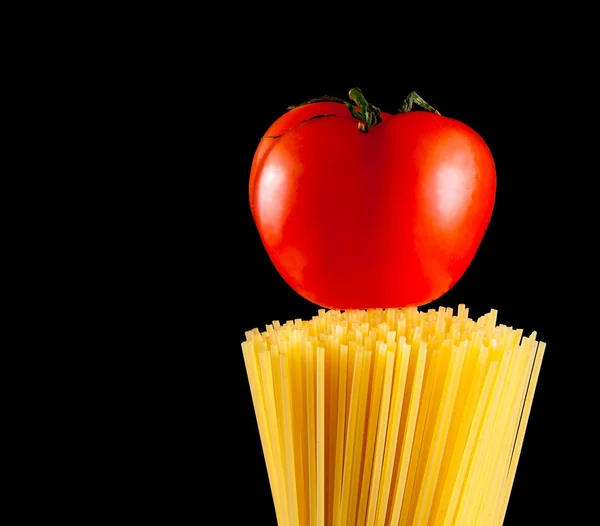 Ruwe pasta spaghetti met tomaat op bovenkant op zwarte achtergrond met ruimte voor tekst — Stockfoto