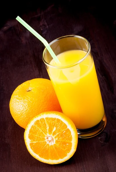 Cima di vista di vetro pieno di succo d'arancia con paglia vicino ad arancia di frutto — Foto Stock