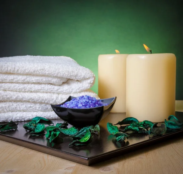 Wellness massage grens achtergrond met handdoek gestapeld, geparfumeerd bladeren, kaars en zee zout — Stockfoto