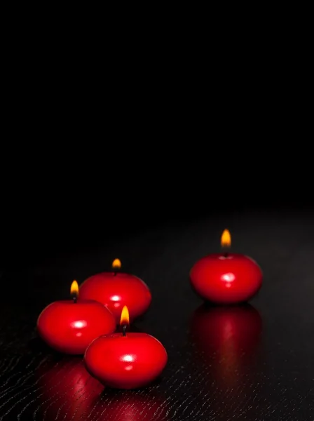 Velas vermelhas com chama em madeira e fundo preto — Fotografia de Stock