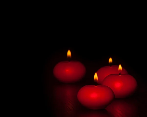 Candele rosse con fiamma su legno e fondo nero, atmosfera scura — Foto Stock