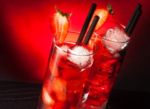 Due bicchieri di cocktail alla fragola con ghiaccio sul tavolo di legno — Foto Stock