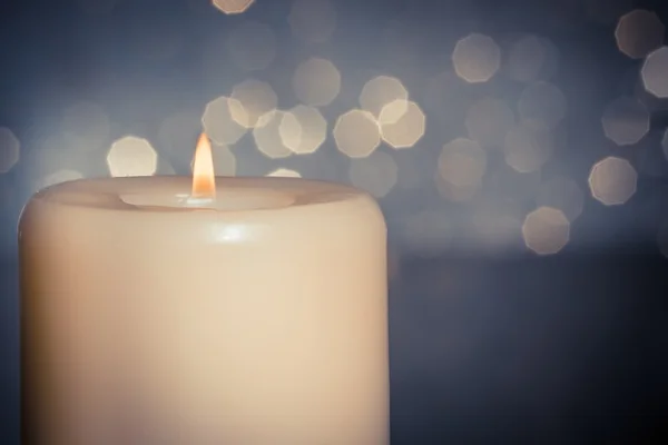 Nahaufnahme einer Kerze mit Flamme auf Holztisch auf blauem Bokeh-Hintergrund — Stockfoto