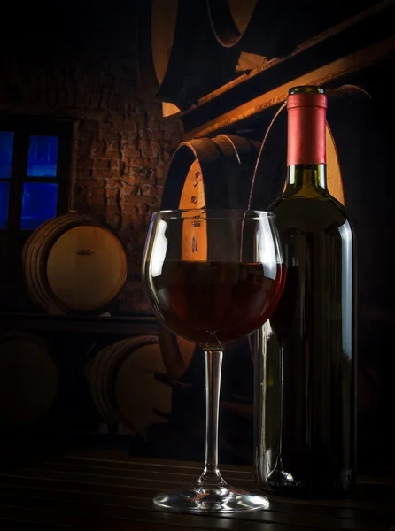 Wine glass near bottle in old wine cellar — Stock Photo, Image