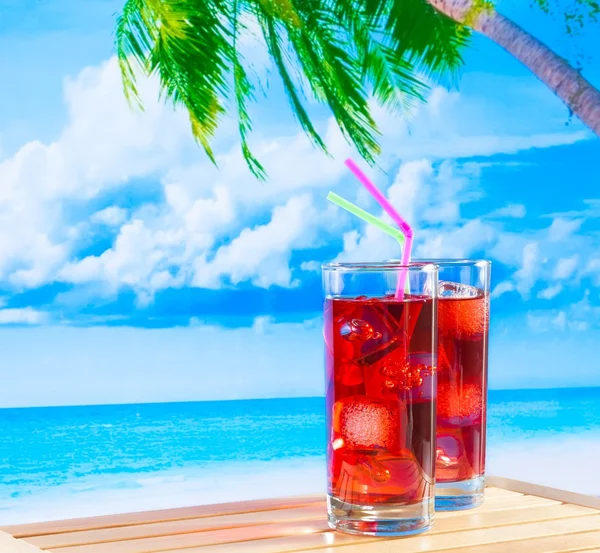 Dwie szklanki czerwony koktajl z plama plaża i palmy — Zdjęcie stockowe