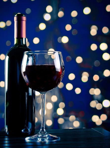 Kieliszek do wina czerwonego w pobliżu butelki z światła bokeh blue — Zdjęcie stockowe
