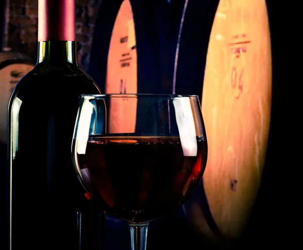 Copa de vino tinto cerca de la botella en el fondo de la bodega vieja con espacio para el texto — Foto de Stock