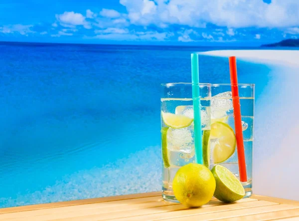 Okulary koktajl z plasterkiem limonki na rozmycie plaży — Zdjęcie stockowe