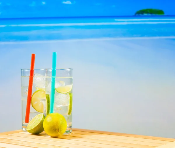 Twee glazen van cocktail met kalk slice op vervagen strand — Stockfoto