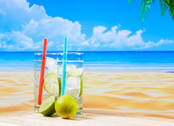 Dwie szklanki koktajlu z plasterkiem limonki na rozmycie plaża i palmy — Zdjęcie stockowe