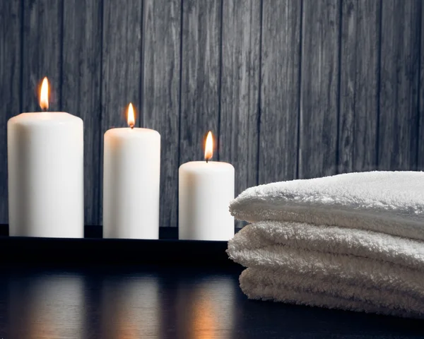 Spa massagem borda fundo com toalha empilhada e velas — Fotografia de Stock