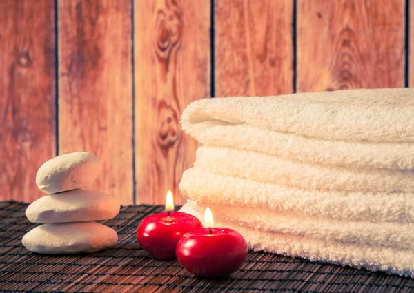 Spa massage gränsen bakgrunden med handduk staplad sten och röda ljus varm atmosfär — Stockfoto