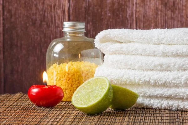 Massage spa avec serviette bougie rouge empilée et citron vert — Photo
