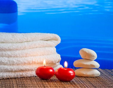 Spa Masaj sınır arka plan ile yığılmış havlu, kırmızı mumlar ve Yüzme Havuzu sınırı yakınında taş