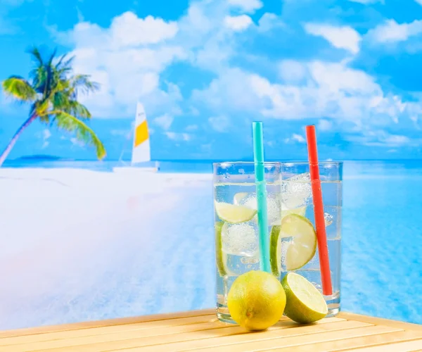 Dwie szklanki koktajlu z plasterkiem limonki na rozmycie plaża i palmy — Zdjęcie stockowe