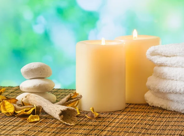 Spa massagem borda fundo com toalha empilhada, velas e pedra — Fotografia de Stock