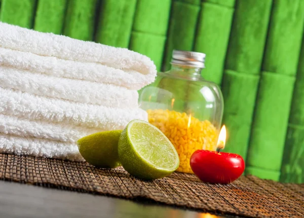 Spa massaggio bordo sfondo con asciugamano impilato, candela rossa e lime — Foto Stock