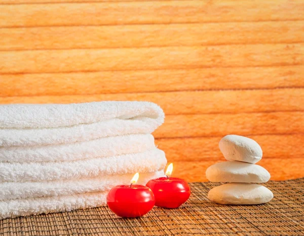 Spa massage gränsen bakgrunden med handduk staplad sten och röda ljus varm atmosfär — Stockfoto