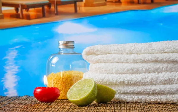 Spa massage gränsen bakgrunden med handduk staplade, rött ljus och lime nära pool — Stockfoto