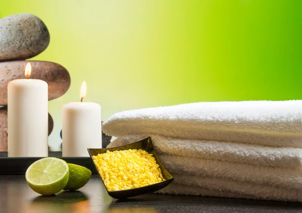 Spa massagem borda fundo com toalha empilhadas velas de sal do mar e limão — Fotografia de Stock