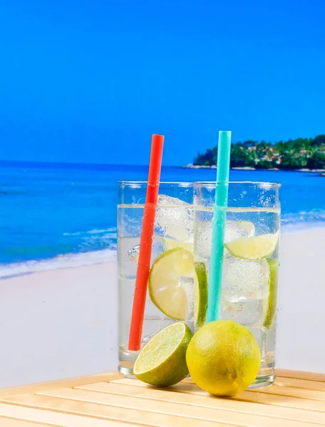 Okulary koktajl z plasterkiem limonki na rozmycie plaży — Zdjęcie stockowe