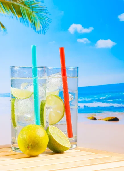 Glazen cocktail met kalk slice op vervagen strand — Stockfoto