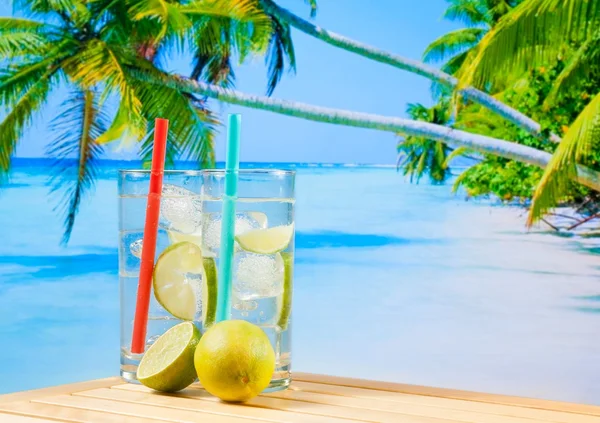 Glazen cocktail met kalk slice op vervagen strand en palm — Stockfoto