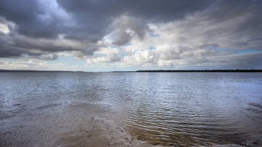 Queensland, Poona Sahili 'nde deniz ve plajda dramatik fırtına bulutları kopuyor. Panorama, Büyük Kumsal Boğazı 'nı geçip Fraser Sahili boyunca ufka doğru bakıyor..