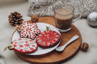 Noel kompozisyonu zencefilli kurabiye ve tahta bir tahtanın üzerinde kahve. Tabakta nefis yemekler. Keyifli bir atmosfer. Süt desenli arka plan ve süveter.