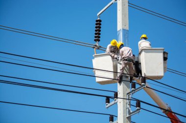 Bir grup erkek mühendis ya da elektrikçi elektrik direğinin üzerinde Crane Bucket üzerinde çalışıyorlar.