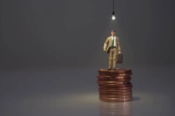 Miniaturní Muž Stojící Hromadě Mincí Zářící Žárovkou — Stock fotografie
