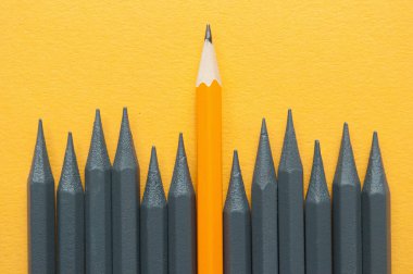 Orange pencil standing out amongst grey pencils
