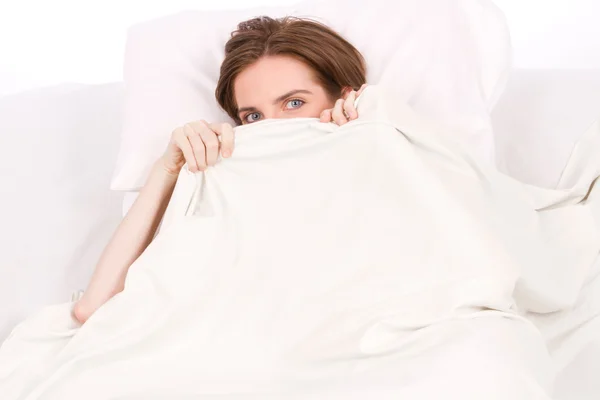 Девушка прячется под белым одеялом — стоковое фото