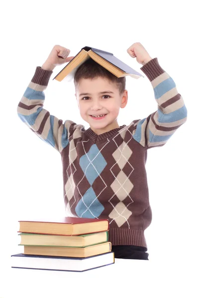 Smiling young boy with a book on his head over white background — Stock Photo, Image