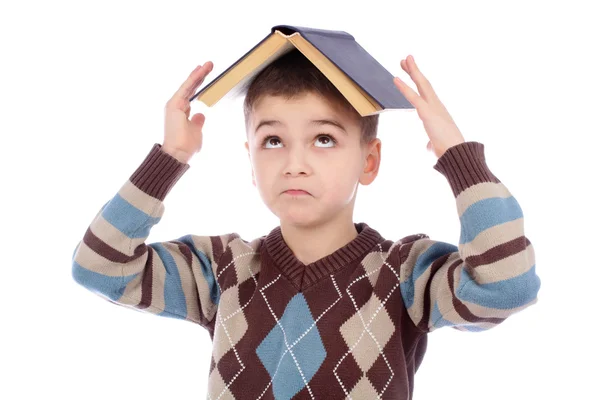 Kleiner Junge mit einem Buch auf dem Kopf vor weißem Hintergrund — Stockfoto