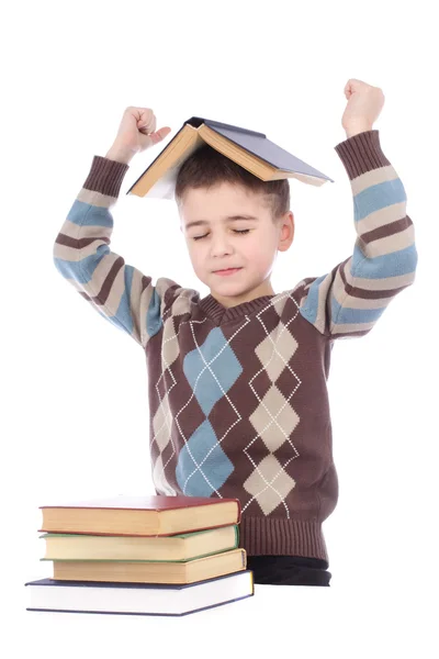 Niño sonriente con un libro en la cabeza sobre fondo blanco —  Fotos de Stock